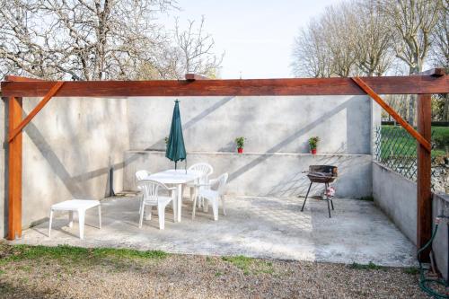 a patio with a table and a umbrella and a grill at L'Ancien relais de poste in La Croix-en-Touraine