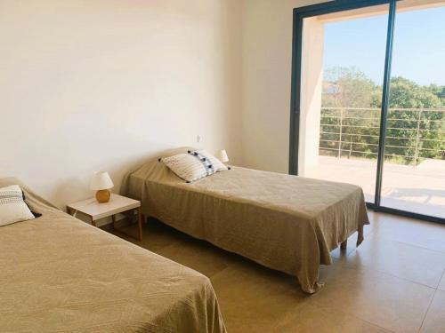 deux lits dans une chambre avec une grande fenêtre dans l'établissement Villa Testa contemporaine, 8 pers, vue mer, piscine, plage à pied, à Olmucciu