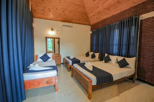 a bedroom with two beds with blue curtains at Yatinuwara Bungalow in Anuradhapura