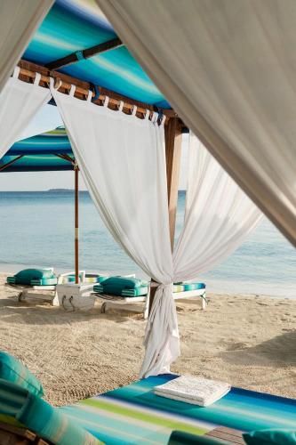 a tent on a beach with chairs and the ocean at One&Only Reethi Rah in Reethi Rah