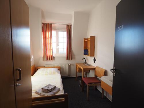 ゲオルクスマリーエンヒュッテにあるHaus Ohrbeckのベッド、デスク、窓が備わるホテルルームです。