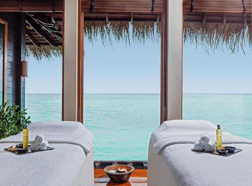 two beds in a room with a view of the ocean at One&Only Reethi Rah in Reethi Rah