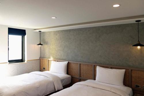 duas camas num quarto com lençóis brancos em Kindness Hotel - Yuanlin em Yuanlin