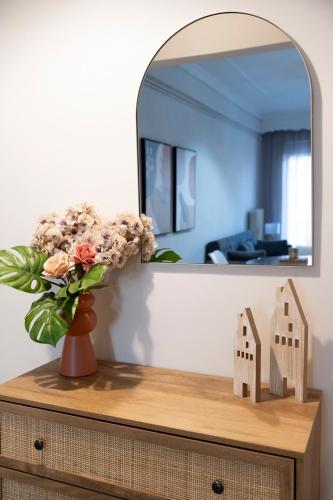 a vase of flowers on a dresser with a mirror at Panagiotidis lake house in Kastoria
