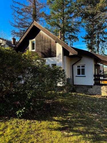 a small white house in a yard with trees at Domek w Karpaczu in Karpacz