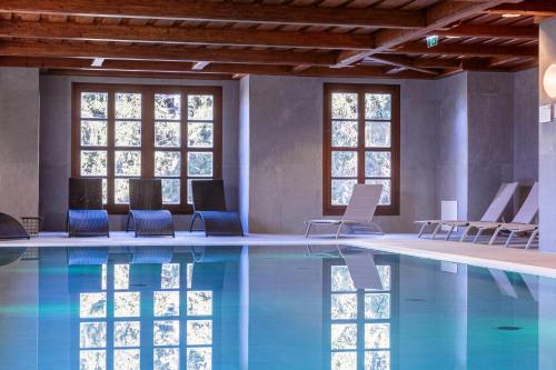 una piscina con sillas azules y ventanas en Bergresort Gerlitzen by ALPS RESORTS, en Treffen