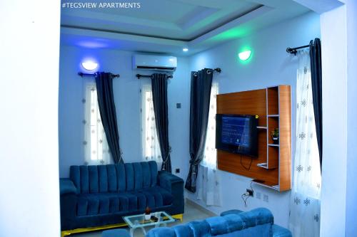 a living room with a blue couch and a tv at Tegsview Apartments, Ughelli in Ughelli