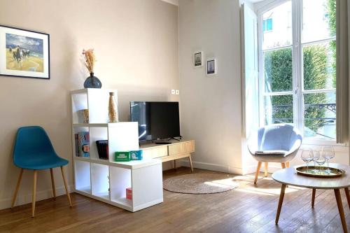 - un salon avec une télévision, une table et des chaises dans l'établissement Le Mario-Cosy appart au calme proche centre, à Nantes