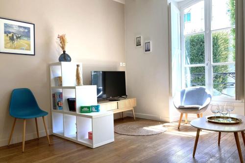 un salon avec une télévision, une table et des chaises dans l'établissement Le Mario-Cosy appart au calme proche centre, à Nantes