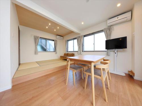 a dining room with a table and chairs and a flat screen tv at COTO Tokyo Shibuya 4 in Tokyo