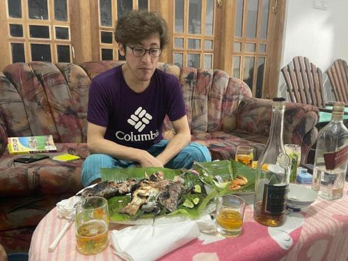 un hombre sentado en un sofá con una mesa con un plato de comida en Shenumi villa en Waskaduwa