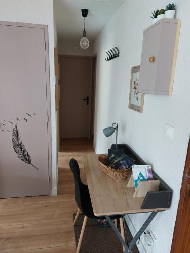 Zimmer mit einem Tisch, einem Stuhl und einer Tür in der Unterkunft Appartement en résidence proche du plan d'eau in Embrun