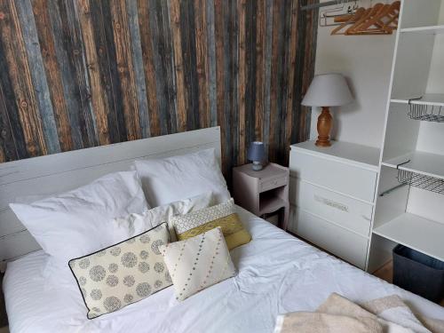 un letto con lenzuola e cuscini bianchi in una camera da letto di Appartement en résidence proche du plan d'eau a Embrun