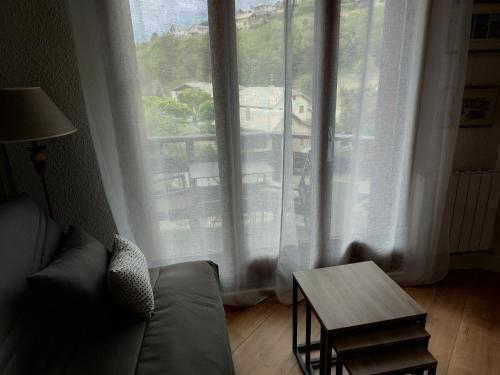 un soggiorno con divano e una grande finestra di Appartement en résidence proche du plan d'eau a Embrun