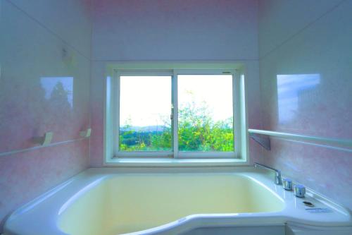 a bath tub in a bathroom with a window at Yuushin in Mifune