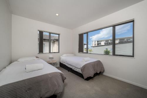オークランドにある7BR 3BH Beach Escape. 2 min to Browns Bay Beachの窓が2つある部屋にベッドが2つある