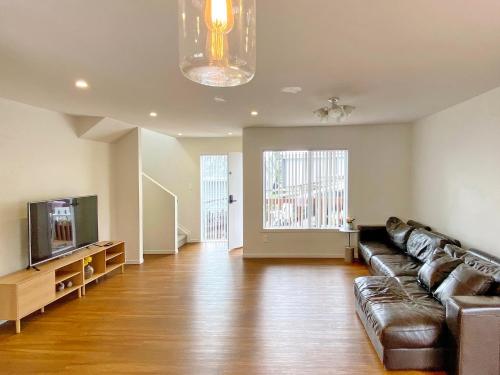 a living room with a couch and a tv at Browns Bay Spacious Retreat- near Beach & Shopping in Auckland