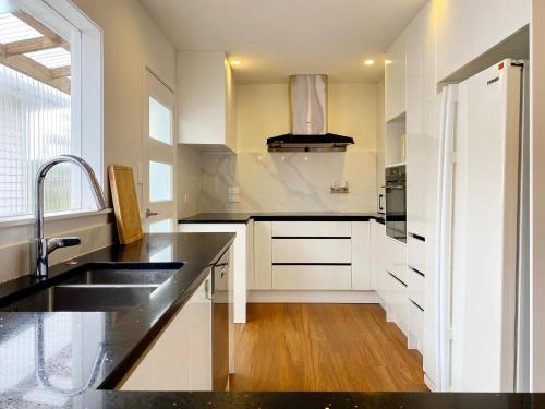 a kitchen with white cabinets and a black counter top at Browns Bay Spacious Retreat- near Beach & Shopping in Auckland