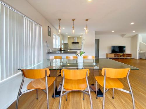 a dining room with a glass table and chairs at Browns Bay Spacious Retreat- near Beach & Shopping in Auckland