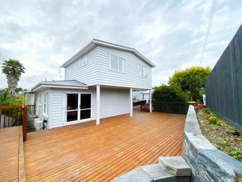 a house with a wooden deck in front of it at Browns Bay Spacious Retreat- near Beach & Shopping in Auckland