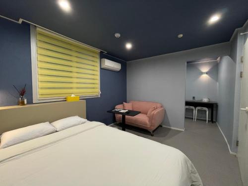 a bedroom with a bed and a chair and a window at Hotel Stay Q in Daejeon