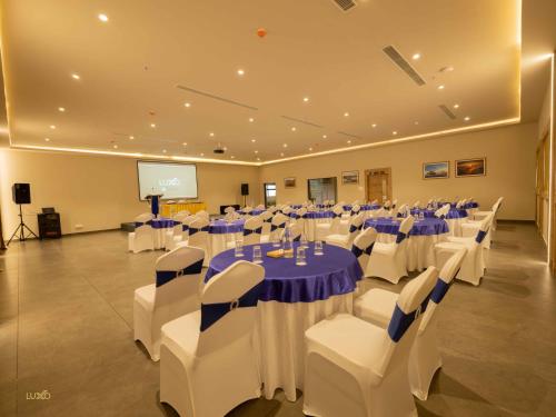 a conference room with tables and chairs and a screen at Luxo Kochi in Ernakulam
