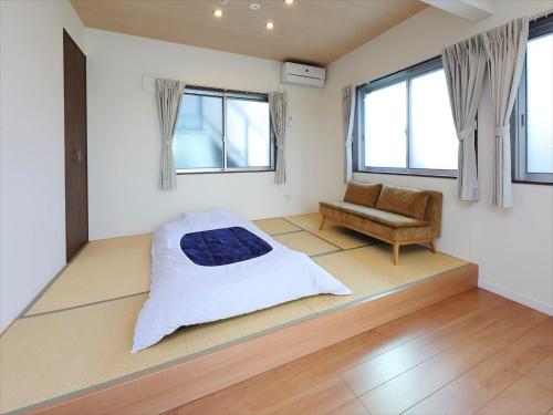 a bedroom with a bed and a couch and windows at COTO Tokyo Shibuya 4 in Tokyo