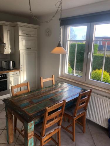 een keuken met een houten tafel met stoelen en ramen bij Pension Villa Wolkenlos in Dahme