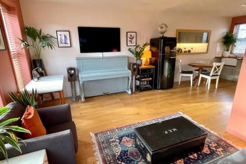 a living room with a couch and a piano at Charming and Spacious 2 Bed Near Kensal Green Tube in London