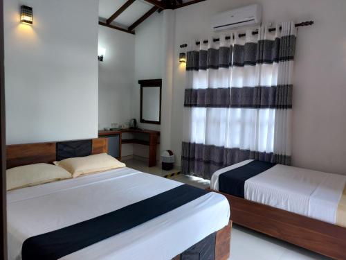 una camera d'albergo con due letti e una televisione di Green Shield Resort a Anuradhapura