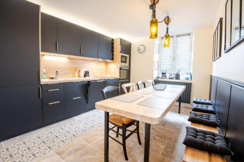 a kitchen with black cabinets and a wooden table at Maison paradisiaque avec piscine in Mosnes