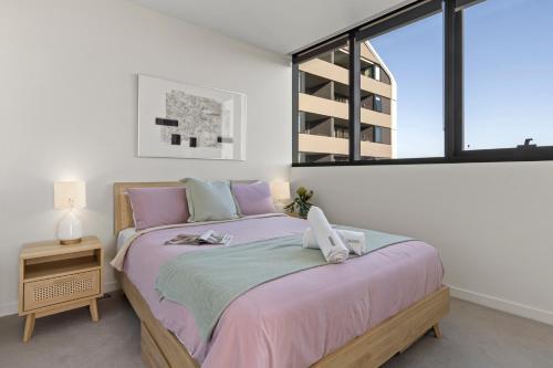 a bedroom with a bed with pink sheets and a window at Zi apartments - with Balcony, Bayview, Sauna and Pool in Melbourne