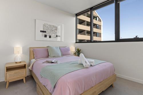 una camera da letto con un letto con lenzuola rosa e una finestra di Zi apartments - with Balcony, Bayview, Sauna and Pool a Melbourne