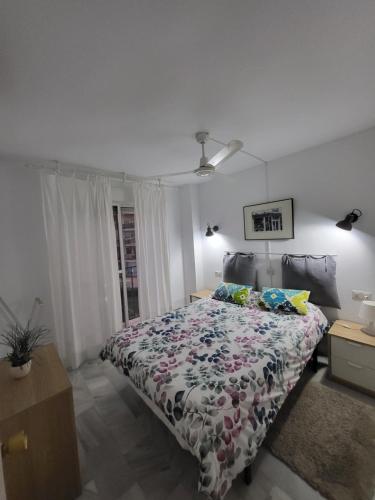 um quarto com uma cama com colcha floral em Apt Erisa en Torremolinos dos min de la playa, Puerto Marina em Torremolinos