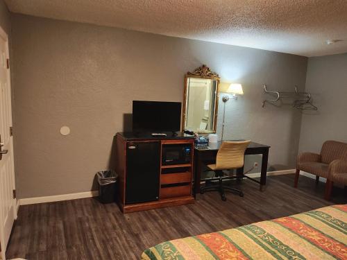a hotel room with a bed and a desk with a television at Economy Inn Richmond in Richmond