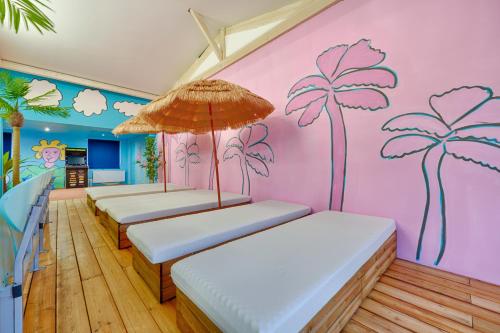 Morsang-sur-SeineにあるVilla California Dream proche paris et disneyのヤシの木が壁に並ぶベッド4台が備わる客室です。