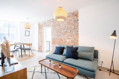 a living room with a blue couch and a brick wall at Parenthèse lumineuse au cœur d’Amboise in Amboise