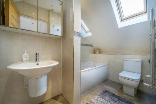 La salle de bains est pourvue d'un lavabo, de toilettes et d'une fenêtre. dans l'établissement Executive Residence - Yorkshire Staycation Home, à Gomersal