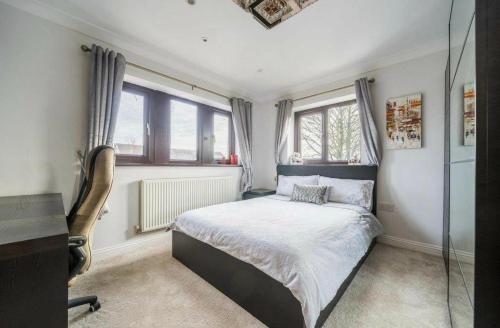 a bedroom with a bed and a desk and windows at Executive Residence - Yorkshire Staycation Home in Gomersal