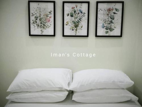 4 cuadros en una pared sobre una cama con 4 almohadas en Iman’s Cottage Hospital Kulim Hitech, en Kulim