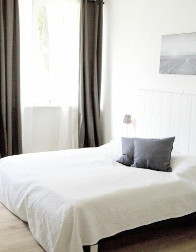 Schlafzimmer mit einem weißen Bett und einem Fenster in der Unterkunft Ferienwohnung Charlotte in Glücksburg