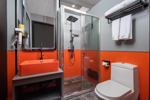 an orange bathroom with a toilet and a shower at Banana Fun Hotel - Guangzhou East Railway Station Yantang Metro Station in Guangzhou