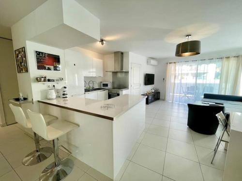 une grande cuisine blanche avec un comptoir et des chaises dans l'établissement Appartement centre de Cannes - 2 pièces - Garage, à Cannes