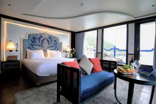 Lotus D'Orient Cruise في ها لونغ: غرفة نوم بسرير واريكة وطاولة