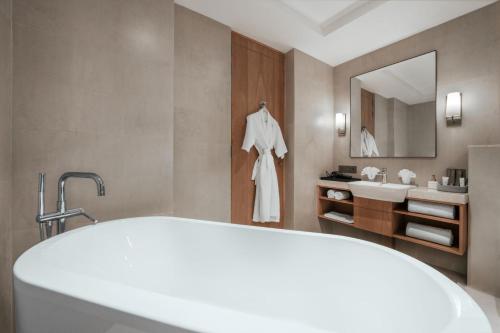 a bathroom with a bath tub and a sink at The Astor - All Suites Hotel Candolim Goa in Candolim