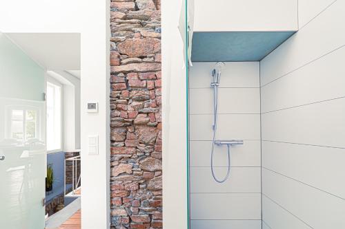 y baño con ducha y pared de piedra. en Komló Apartman - Mátyás, en Kőszeg