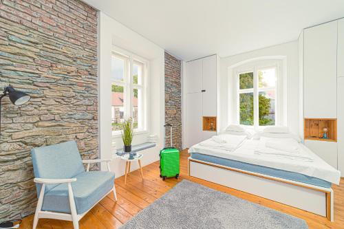 a bedroom with a bed and a chair and a brick wall at Komló Apartman - Mátyás in Kőszeg