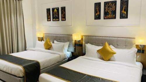 two beds in a hotel room with yellow pillows at The Shankara View in Godarpura
