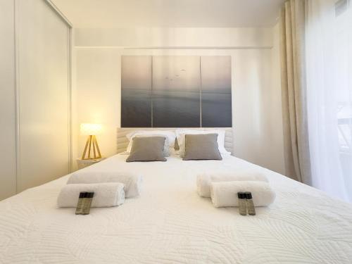 une chambre avec un grand lit blanc avec deux oreillers dans l'établissement Le Doré by Winsome Destination, à Cannes