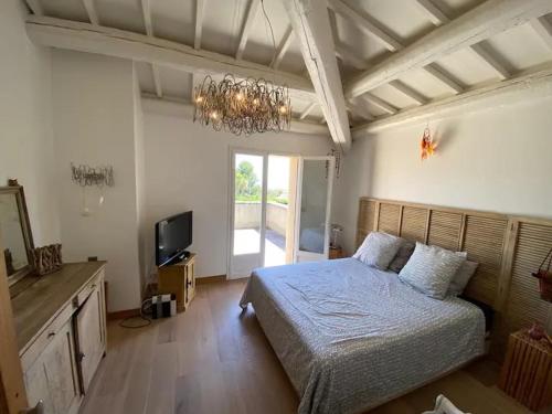 - une chambre avec un lit, une télévision et un lustre dans l'établissement Mas Carpe Diem Contemporain classée 3 étoiles -Piscine-A 400 m de la mer, à Carry-le-Rouet